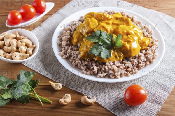 Buckwheat with chicken curry sauce with cashew on brown wooden background. close up
