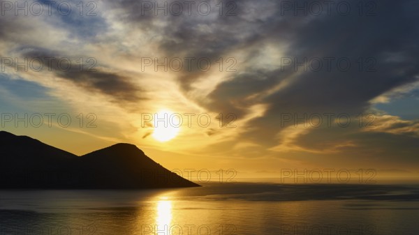 Sunrise by the sea with mountains, dramatic clouds and golden light, Mani Peninsula, Peloponnese,