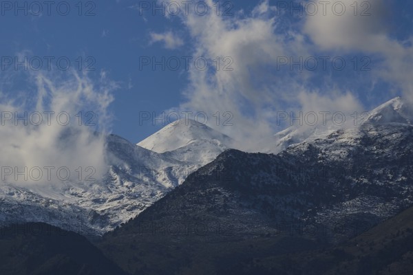 Mountain peaks with snow and clouds under a blue sky, Lefka Ori, White Mountains, mountain massif,
