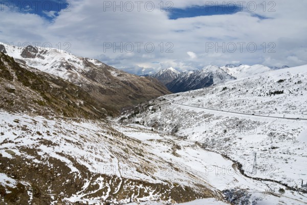 Winterliche Landschaft in den schneebedeckten Bergen von Andorra mit einer Straße und Wolken am