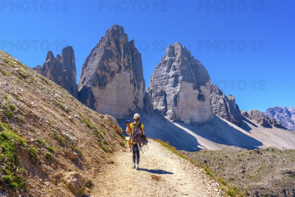 Tourists walking on a mountain path near tre cime di lavaredo, dolomites, a famous landmark in