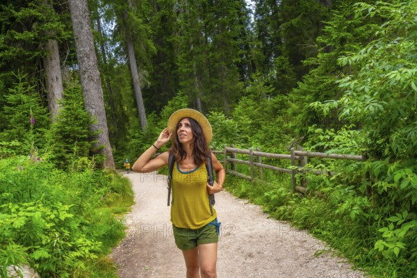Female tourist enjoying a walk along a forest trail near lake carezza in the italian dolomites