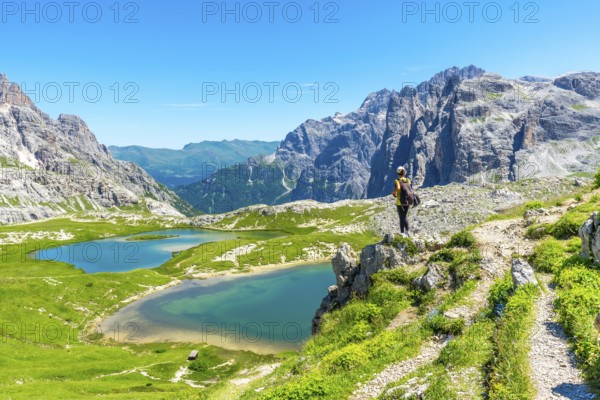 Hiker enjoying the breathtaking view of the tre cime di lavaredo peaks and the turquoise alpine