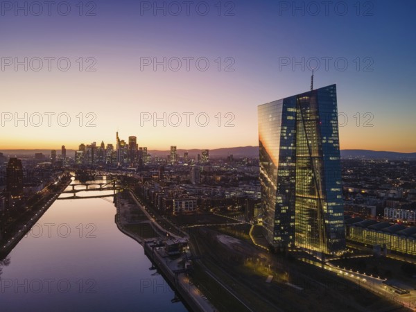The lights in the offices of the European Central Bank (ECB) and the Frankfurt skyline glow in the