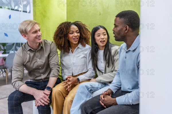 Four colleagues from diverse backgrounds are having a productive discussion in a modern coworking