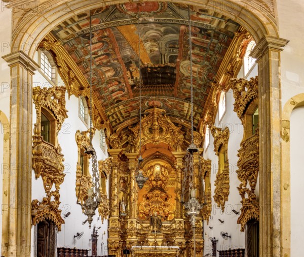 Interior and altar of a historic baroque church richly decorated with gold leaf ornaments and