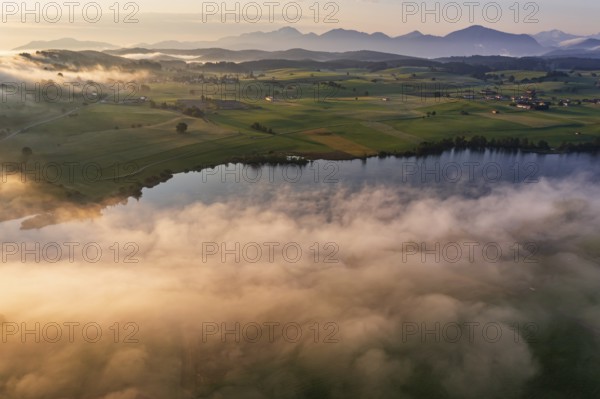 Aerial view of a lake in front of mountains in the morning light, fog, autumn, Riegsee, view of