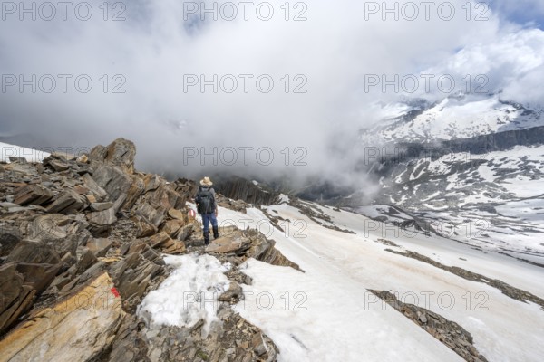 Mountaineer on a rocky ridge with snow, descent from the summit of Schönbichler Horn, view of
