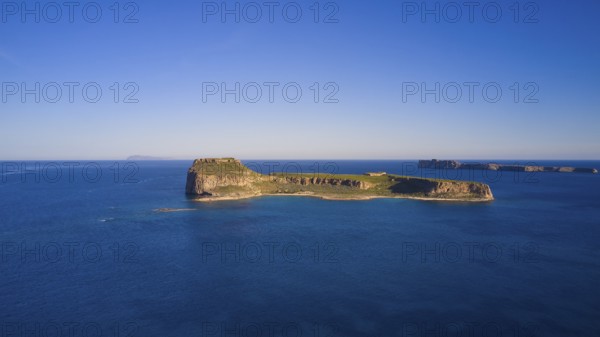 Drone shot, A deserted island in the vast blue ocean with rocky coastlines and clear skies,