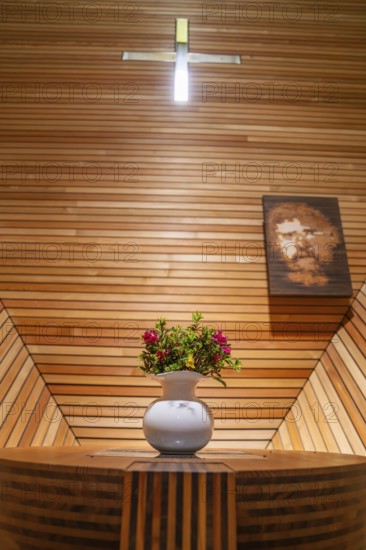 Flower arrangement on an altar table in a modern, wood-panelled interior with cross, Penken,