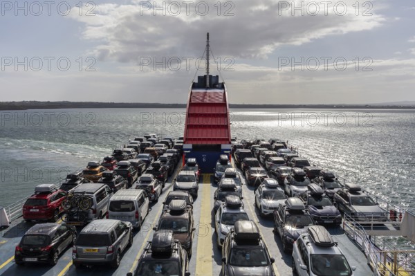 Ferry loaded with cars, sun reflected on the sea, bright sky in the background, Rosslare Harbour