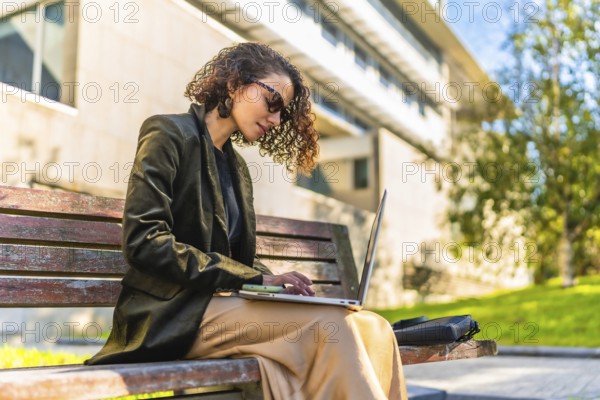 Profile of a beauty young arab businesswoman in casual clothes and sunglasses working with laptop