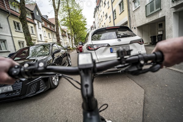 Cycling in the city, city centre street, residential street, 30 km/h zone, traffic with parked cars
