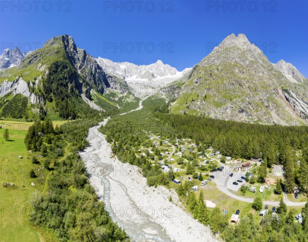 Panoramic aerial view of a campsite at a glacial river, mountain range with glacies in the back, La