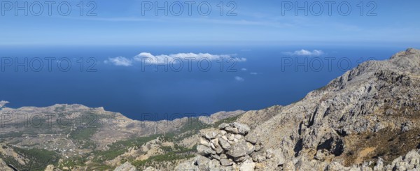 Behind the rocky promontory of the summit of Kali Limni, the bright blue sea of the west side of