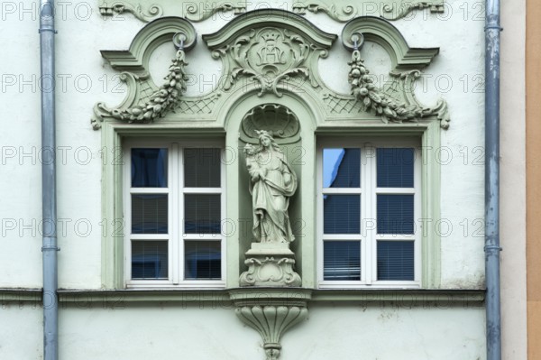 Window framed with figures of saints on a historic façade from 1895, of a former liqueur
