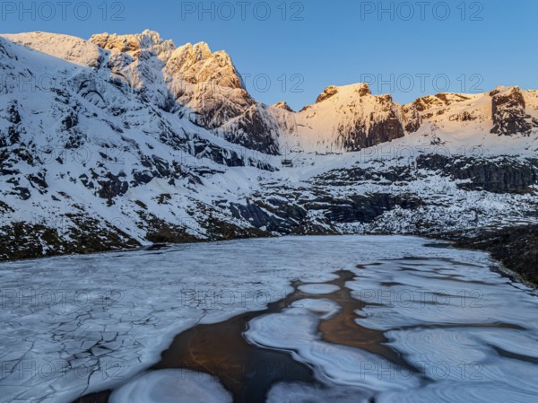Aerial view of icy lake in front of steep mountains, winter, sunrise, Storvatnet, Flakstadoya,