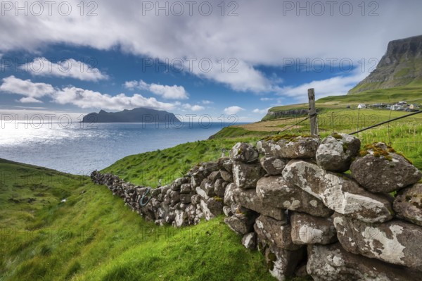 View of the island of Mykines, old stone wall, Gásadalur village, Vágar, Faroe Islands, Denmark,