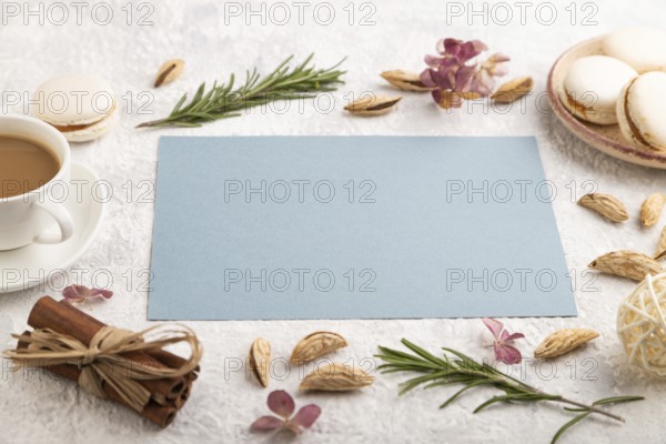 Blue paper sheet mockup with cup of coffee, almonds and macaroons on gray concrete background.