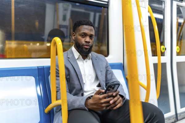 Young businessman sitting on a subway train, using a smartphone during his daily commute, staying