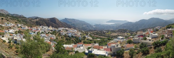 Panoramic view of the village of Othos, mountains and sea under a blue sky, hike from Pyles to