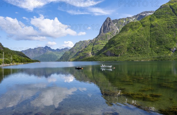Small boats at the fjord Austnesfjorden, idyllic Norwegian fjord landscape, mountains reflected in
