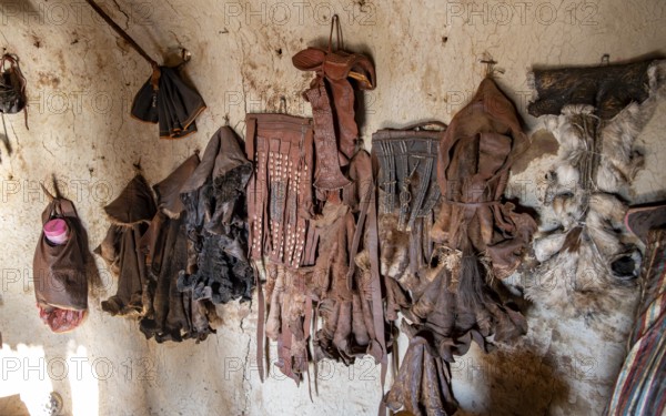 Various traditional leather aprons hanging on the wall, interior of a mud hut of the first woman in