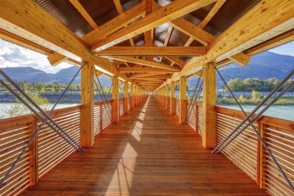 Symmetrical interior view of a wooden bridge with a view of the river and mountains, Inn