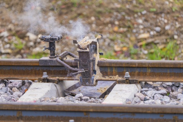 Metal fixture on the rails with rising smoke, rural environment, rail welding, track construction