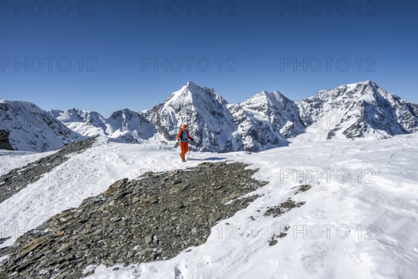 Ski tourers on foot, snow-covered mountain landscape in winter, view of mountain peaks