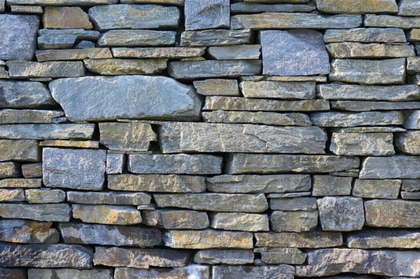 Large, irregular natural stones in various shades of grey form a rustic stone wall, Bergen,