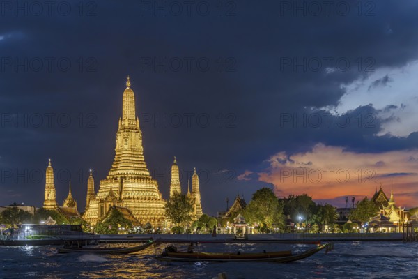 Wat Arun, Temple of Dawn at sunset with dark clouds. Boats on the Chao Phraya river. Tourist
