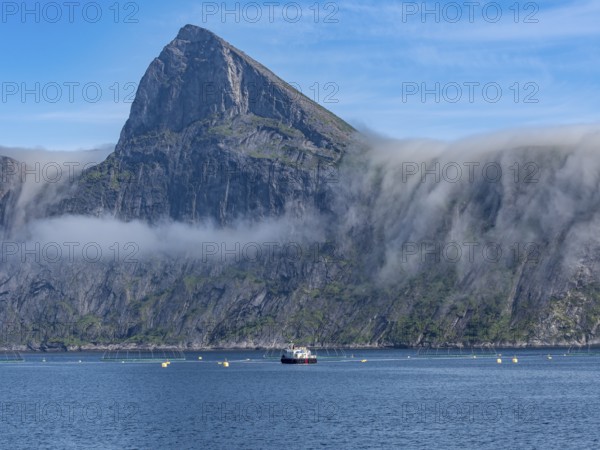 Salmon farm, aquaculture in the Mefjord on Senja island, in the background the peak of famous Segla
