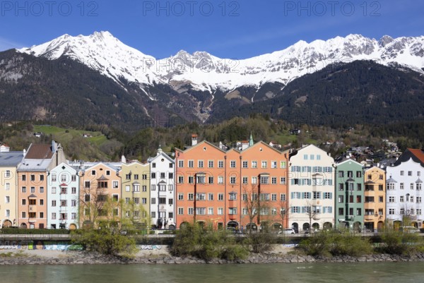 Colourful buildings along the Inn river with snow-covered Nordkette in the background, Karwendel