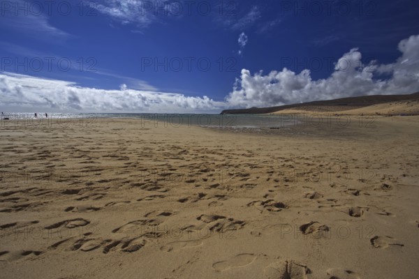 Beach Playa Risco del Paso, Playa de Sotavento with footprints in front of a cloudy blue sky,