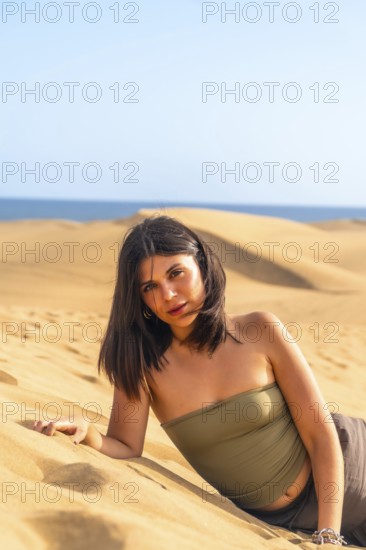 Young woman lying on the sand in the maspalomas dunes, gran canaria, canary islands, spain,