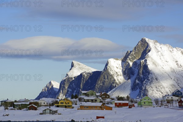 Colourful houses on snowy hills and mountains under a blue sky with few clouds, peaceful winter