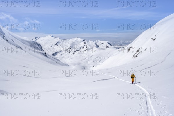 Lone ski tourer in a mountain landscape with snow, summit Wildhorn in the background, ascent to