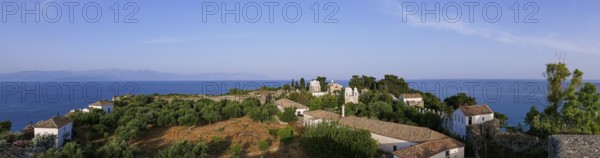 Wide panorama of the whole complex, with church and trees, the sea stretches to the horizon,