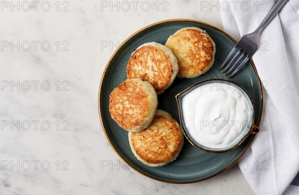 Fried, Cottage cheese pancakes, with sour cream, Cheesecakes, on a marble table, top view, no