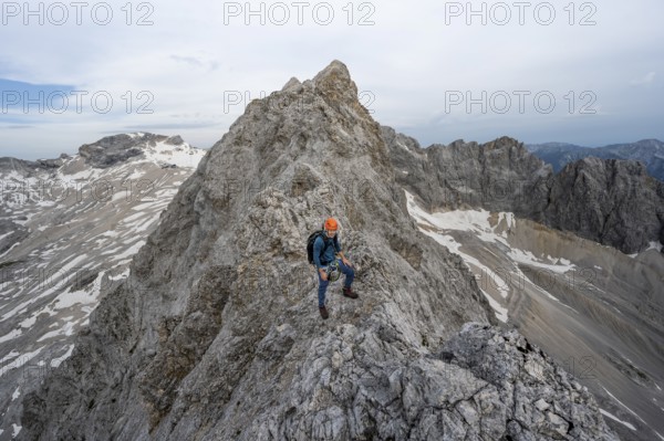 Mountaineer with helmet on a narrow rocky ridge, crossing the Jubiläumsgrat, Wetterstein range,