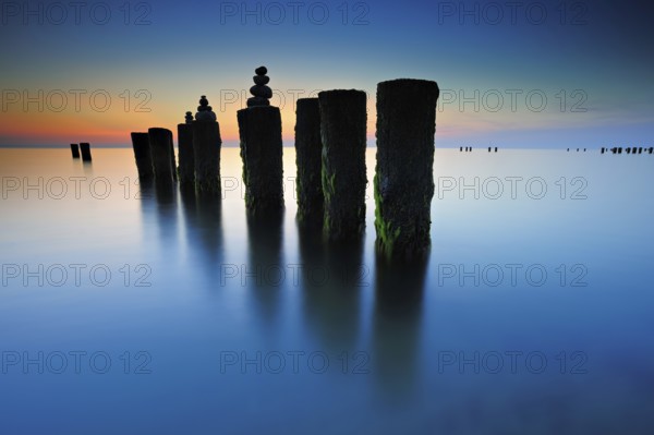Stone pyramids on old groynes with algae in the water on the beach of the Baltic Sea, long exposure