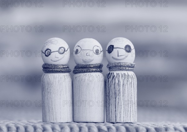 Three small funny wooden cones, monochrome in front of a painted background, North