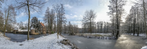 Wide winter landscape near moated castle Haus Welbergen with frozen water and trees,
