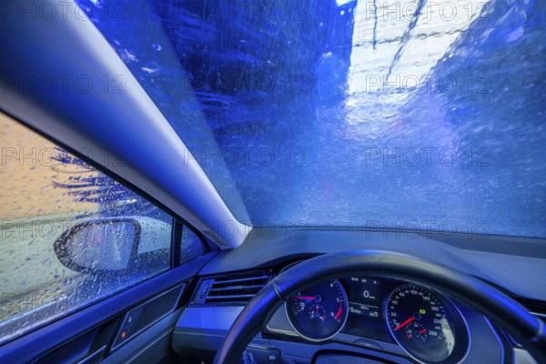 Car in an automatic car wash, car wash tunnel, cleaning foam is sprayed on, rotating brushes clean