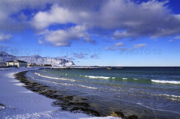 Snowy beach with gentle waves, blue sky and scattered clouds, quiet winter scenery, Ramberg,