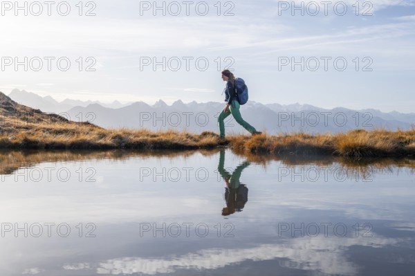 Hiker reflected in a small mountain lake on the Krahberg, mountain panorama in autumn, Venet