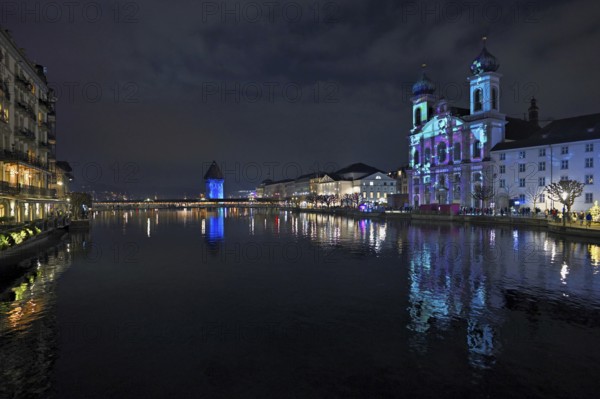 Water tower and Jesuit church on the right with light installation, on the Reuss at dusk, Old Town,