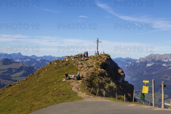 Hiking on the Kitzbüheler Horn in Tyrol: summit cross with a view on a pre-summit just below the