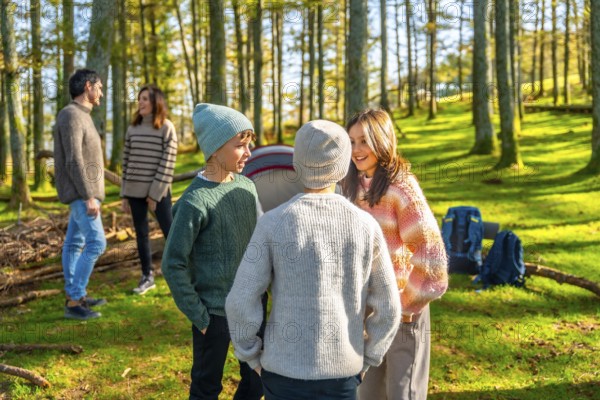 Caucasian family with three teens having fun during a camping in a green alpine forest